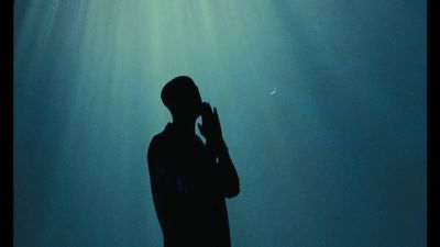 a silhouette of a man standing under water