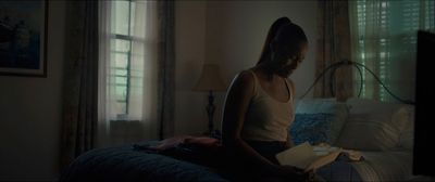 a woman sitting on a bed reading a book