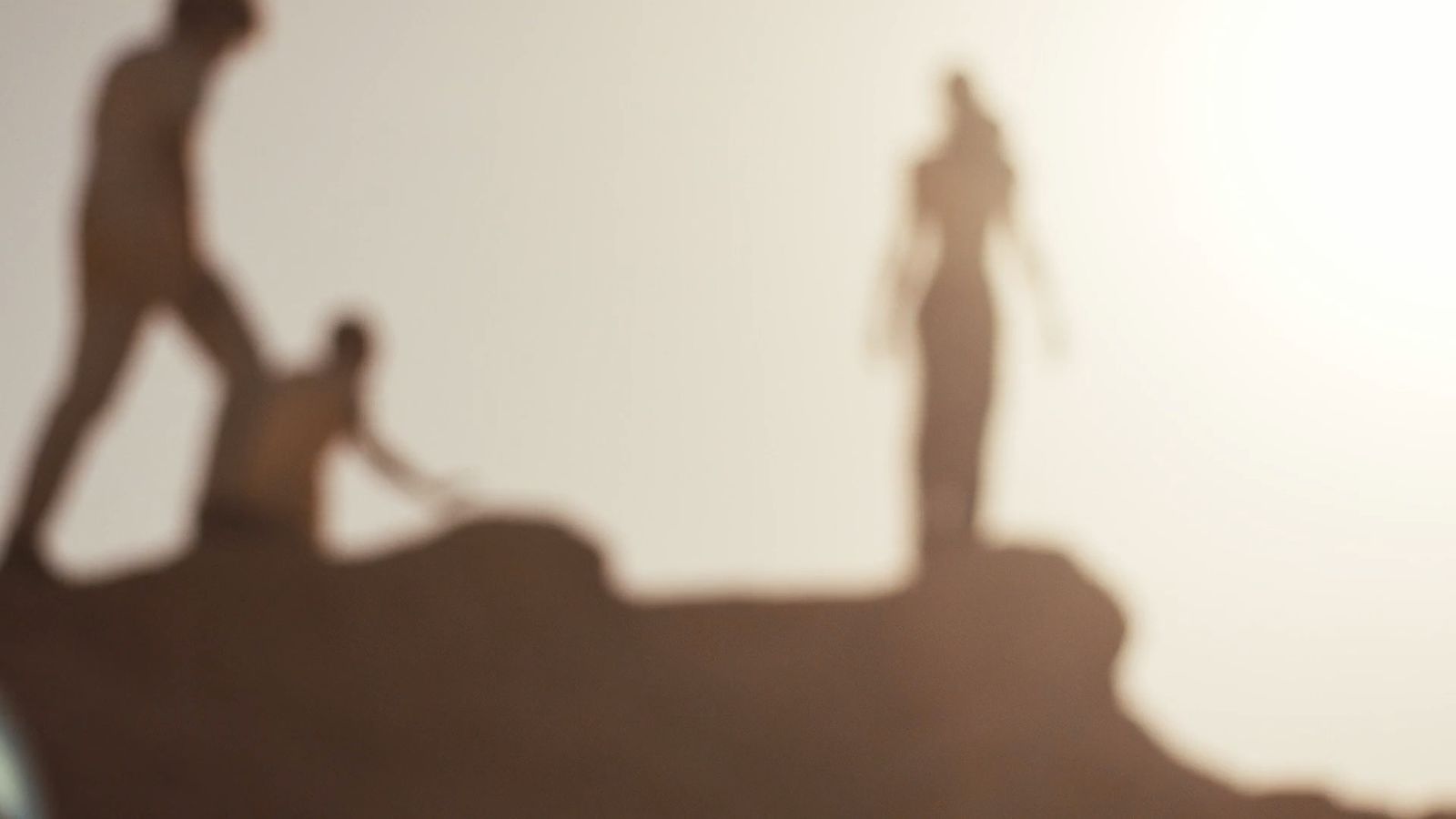 a shadow of two people standing on top of a hill