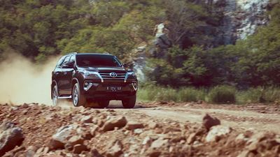 a black suv driving down a dirt road