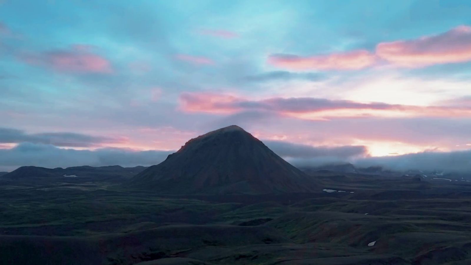 a mountain with a sky filled with clouds