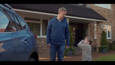 a man standing next to a child in front of a house