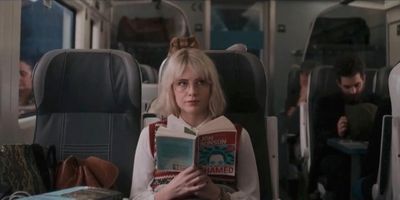 a woman sitting on a train reading a book