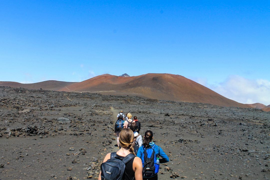 a group of people walking across a dirt field