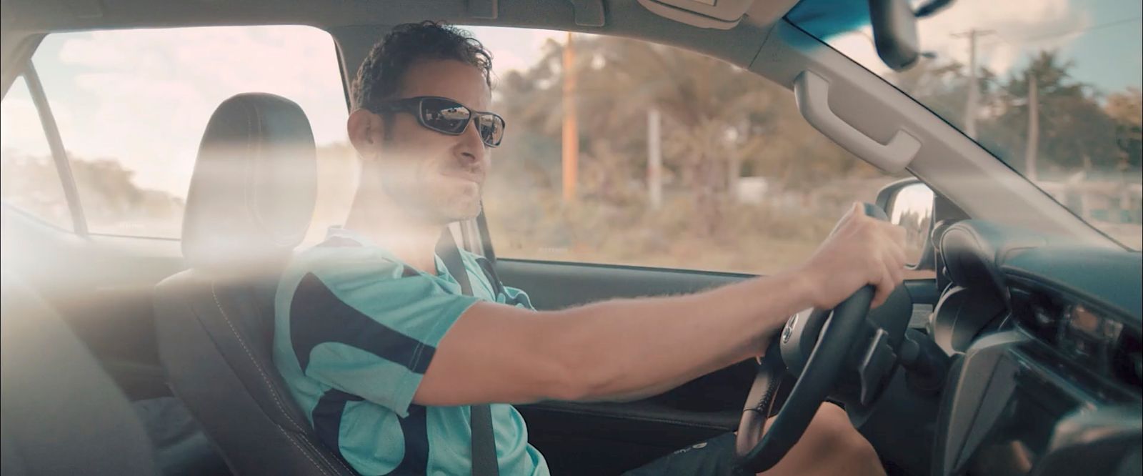 a man driving a car on a sunny day