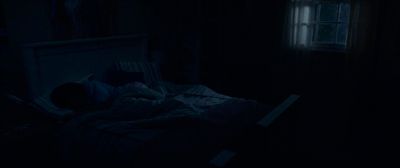 a person laying in a bed in a dark room