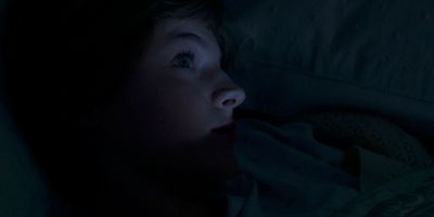 a young child laying in bed in the dark