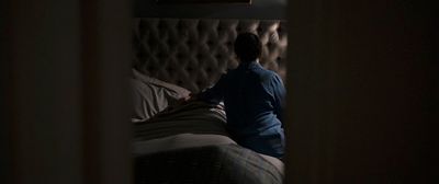 a man sitting on a bed in a dark room