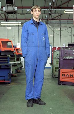 a man in a blue coverall standing in a factory