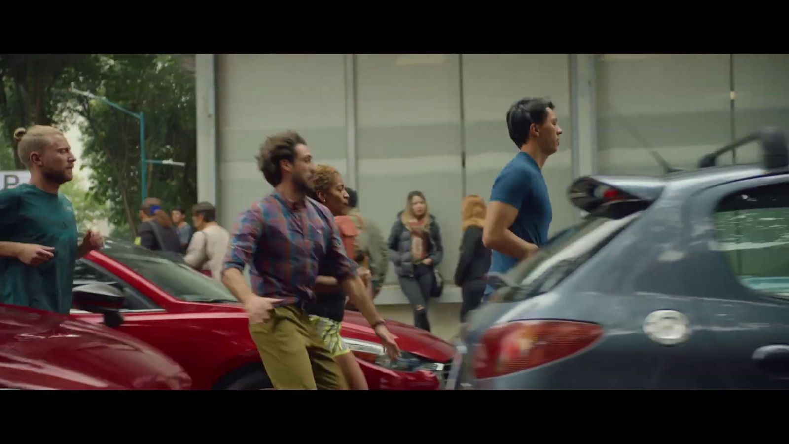 a group of men walking down a street next to parked cars