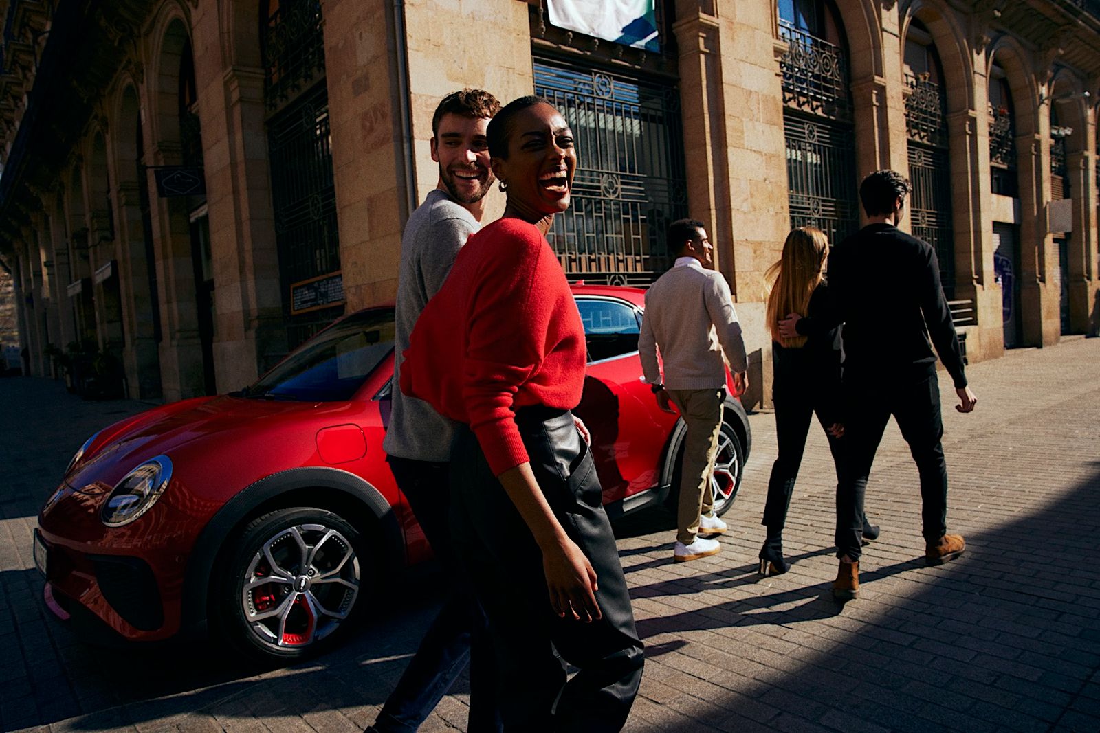 a group of people walking down a street next to a red car