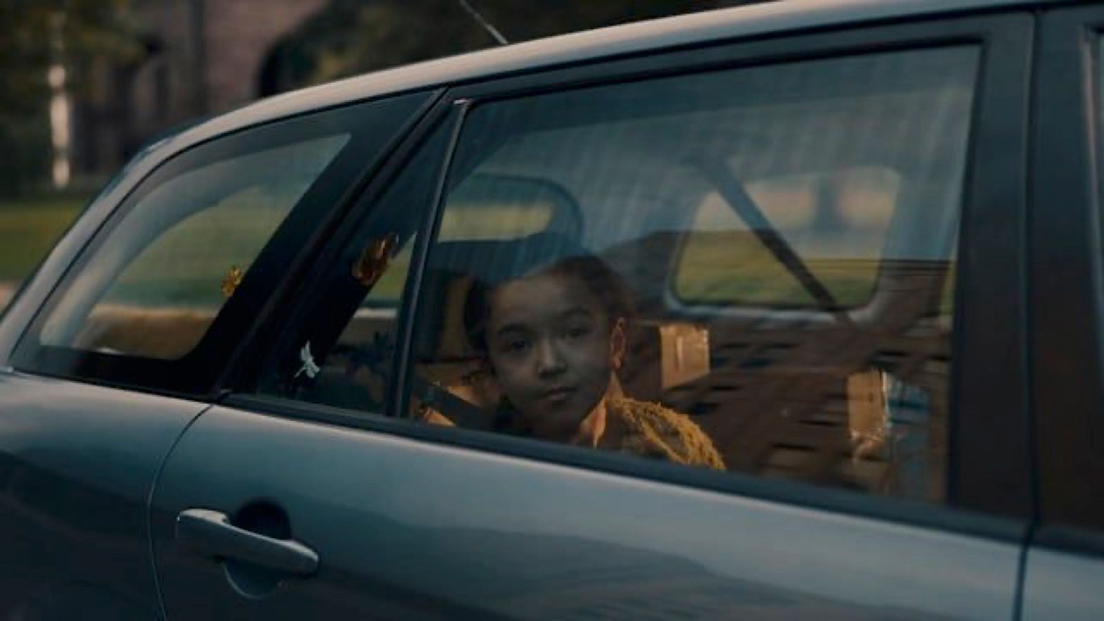 a girl sitting in a car looking out the window