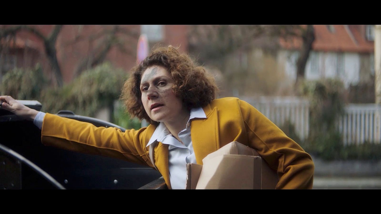 a woman in a yellow jacket leaning out of a car