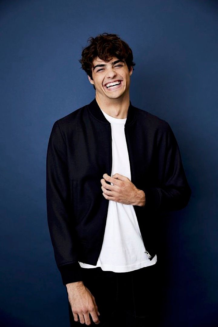 a young man smiling while standing in front of a blue wall