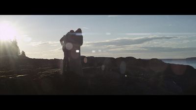 a couple of people standing on top of a rocky beach