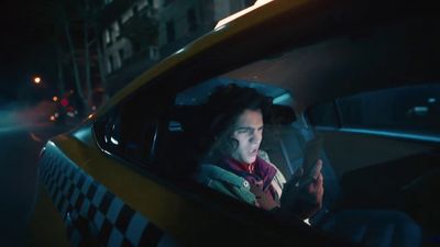 a woman sitting in a taxi looking at her cell phone