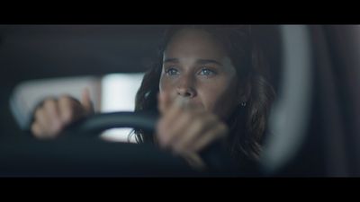 a woman driving a car with her hand on the steering wheel