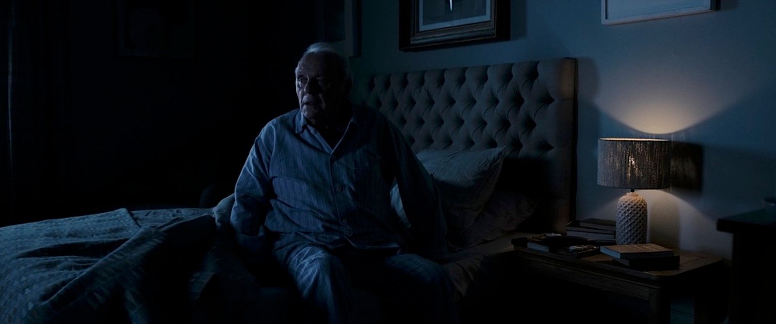 a man sitting on a bed in a dark room