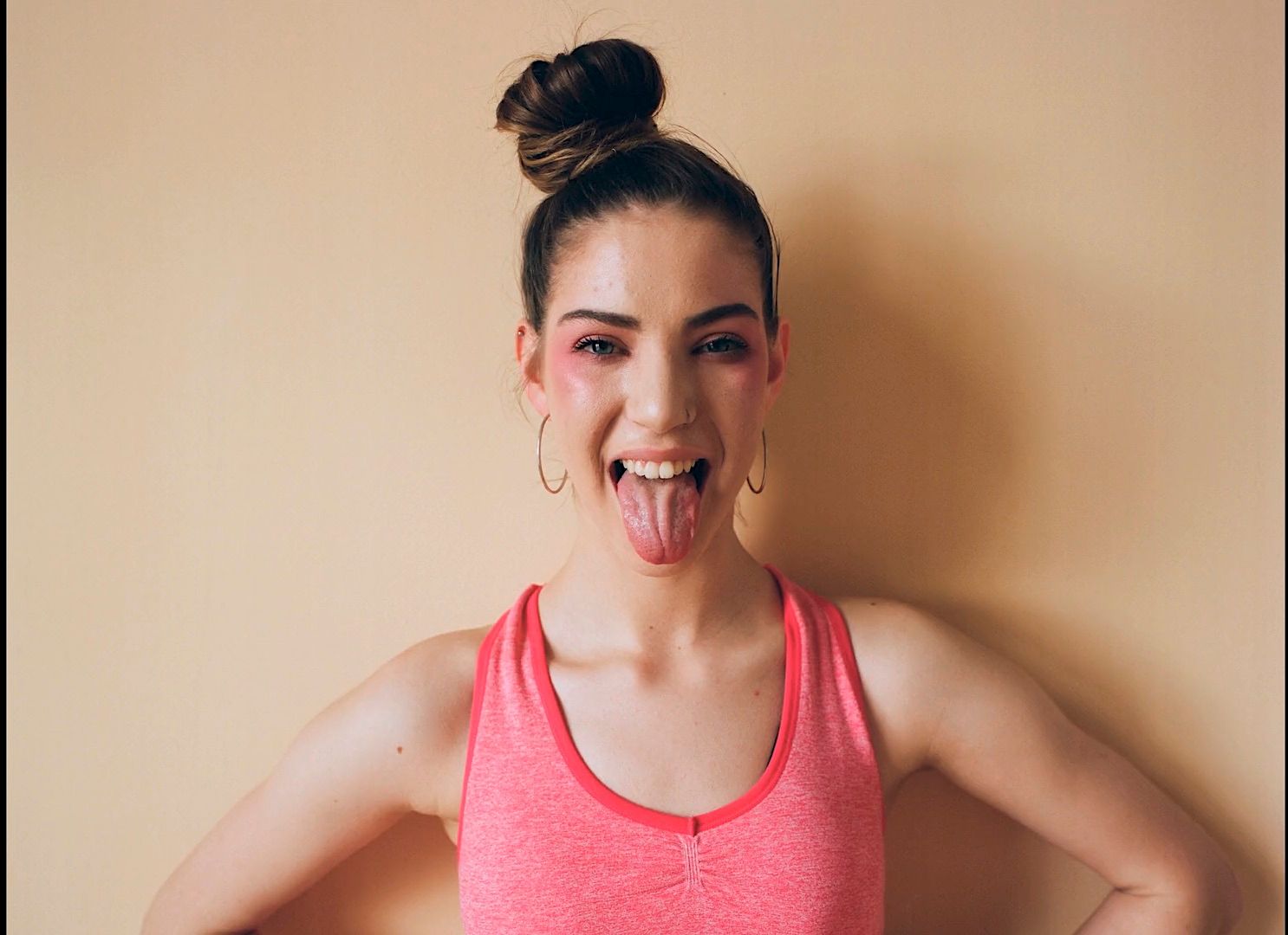 a woman sticking her tongue out in front of a wall