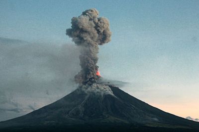 a volcano erupts smoke as it rises into the sky