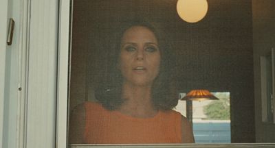 a woman looking out of a window at a lamp