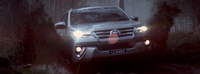 a silver car driving through a forest at night