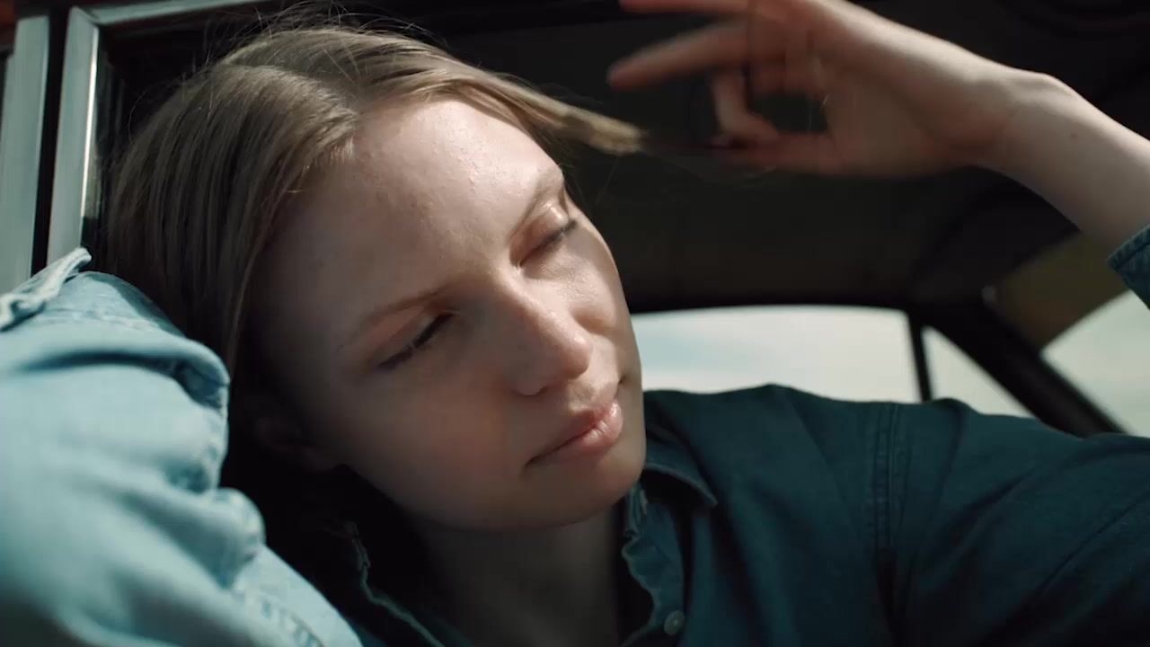 a woman sitting in a car with her hand on her head