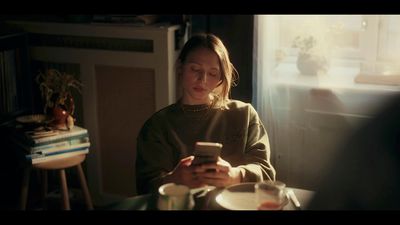 a woman sitting at a table looking at her cell phone