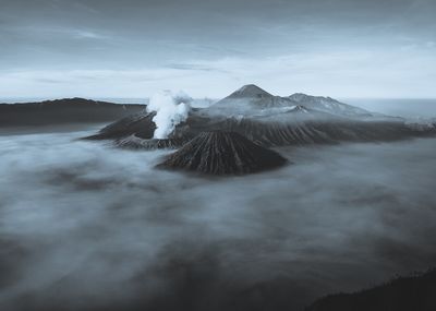 a black and white photo of a mountain covered in fog