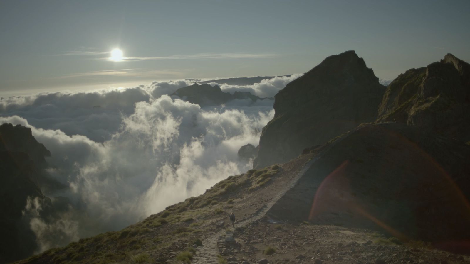 the sun is shining above the clouds in the mountains