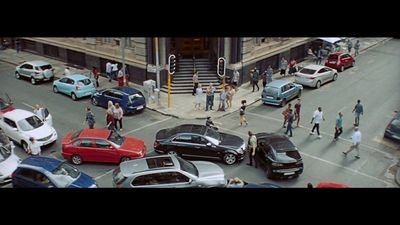 a group of people walking across a street next to parked cars