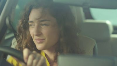 a woman sitting in a car holding a steering wheel