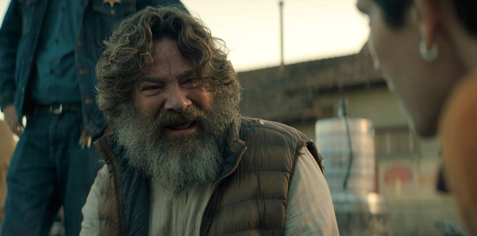 a man with a beard and a vest talking to a woman