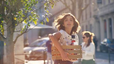 a woman walking down a street carrying a wooden crate