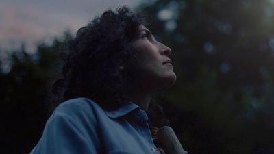 a woman with curly hair looking up at the sky