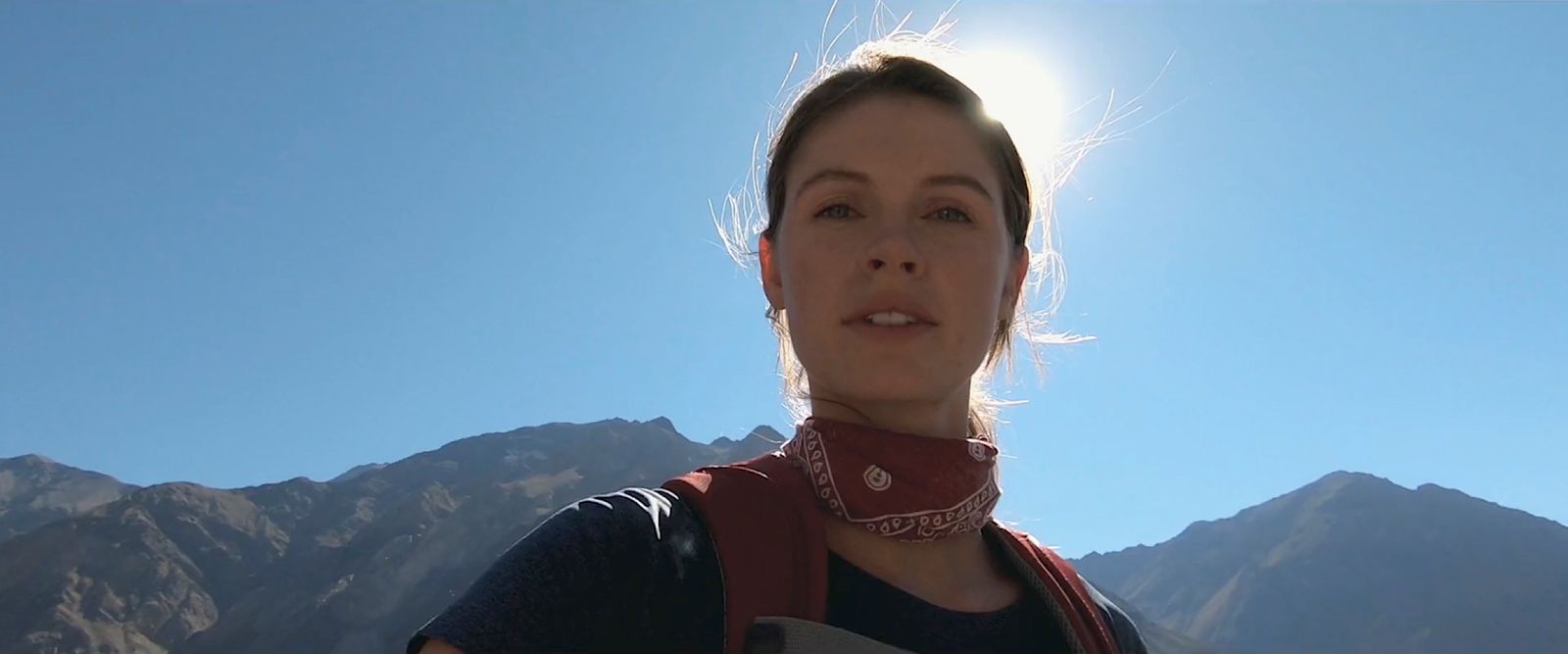 a woman standing in front of a mountain range