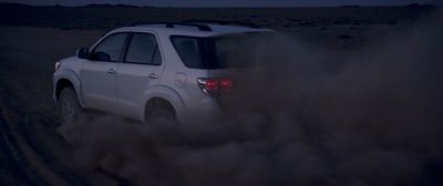 a white suv driving through a desert at night