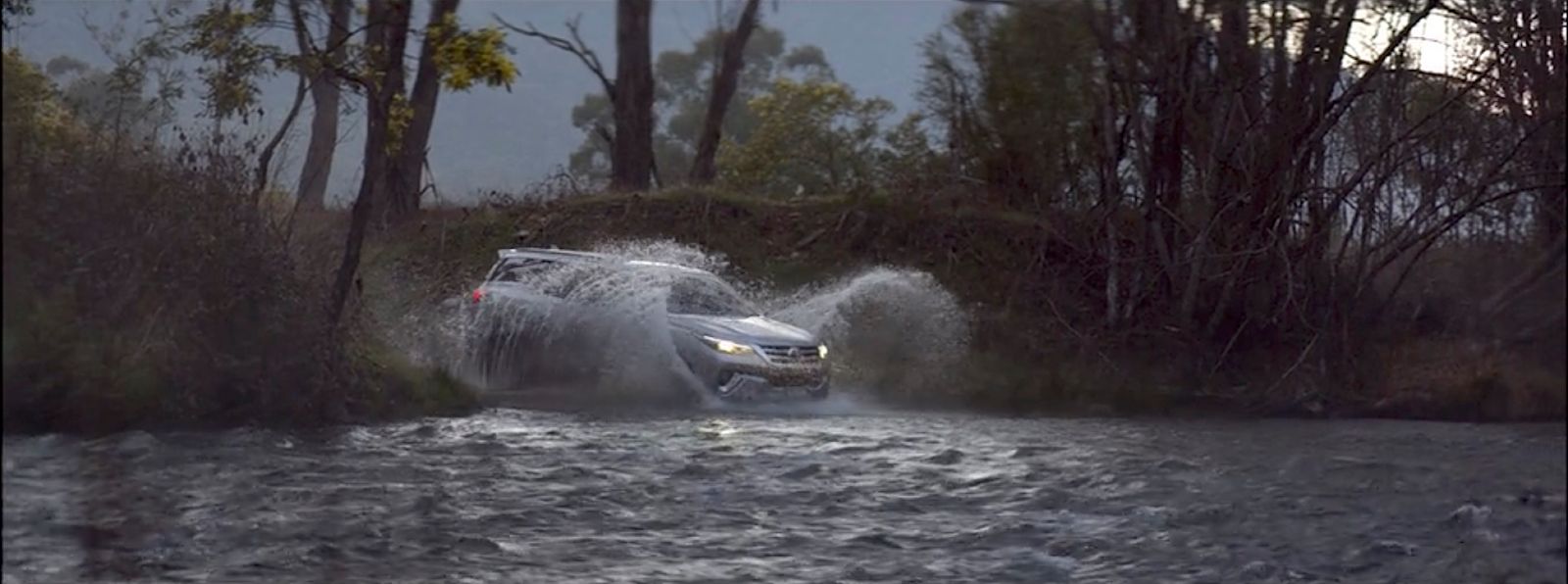 a car is driving through a river in the rain