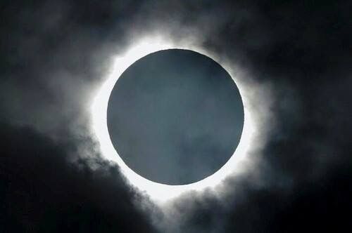 a solar eclipse is seen through the clouds