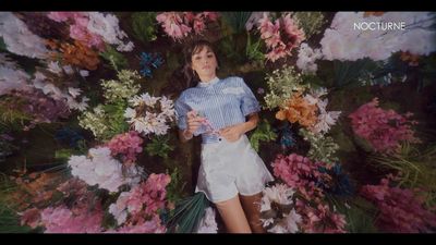 a woman standing in front of a bunch of flowers