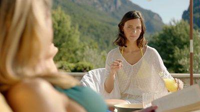 a woman sitting at a table with a book and a drink