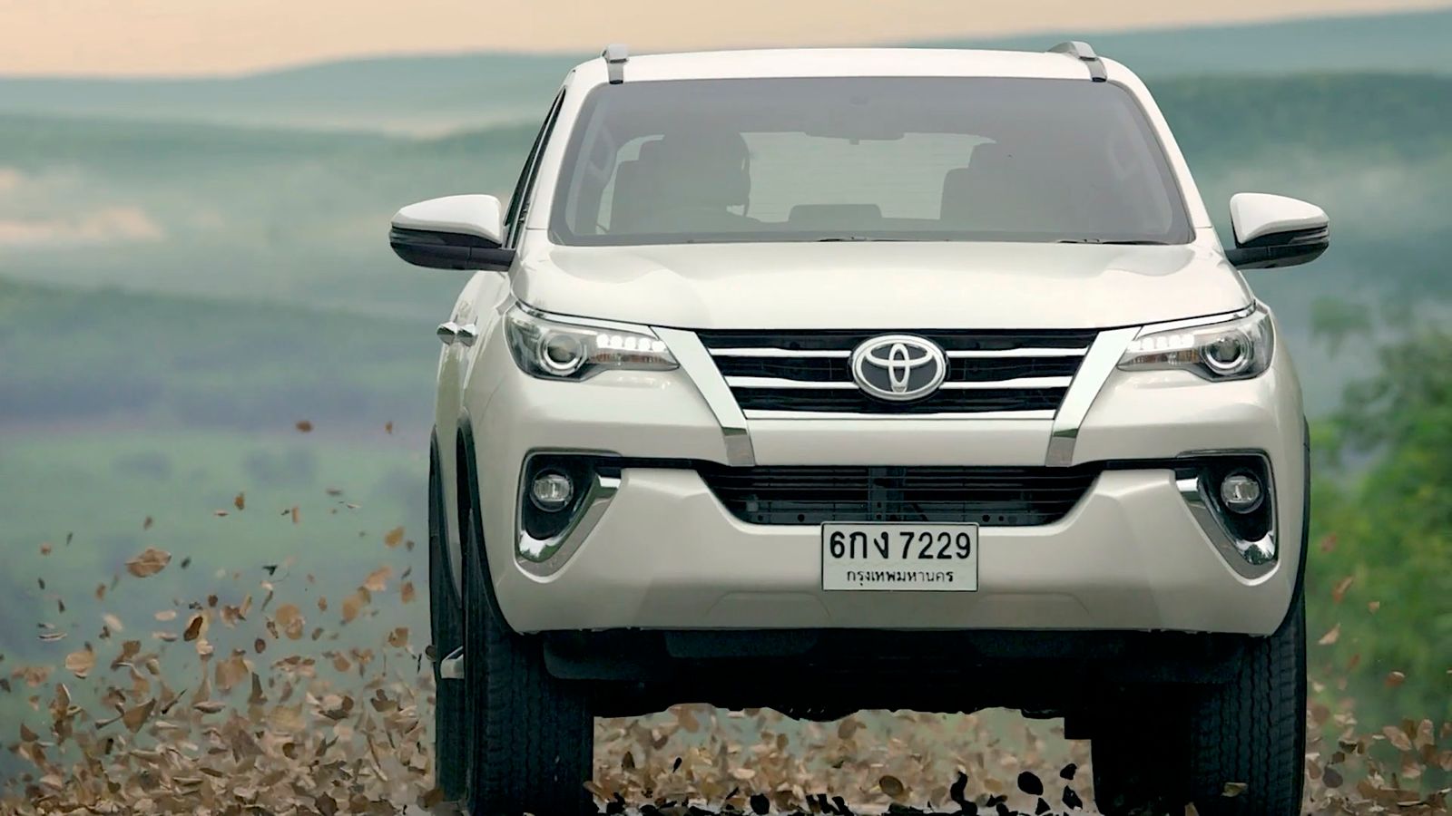 a white toyota fortune is parked in a field