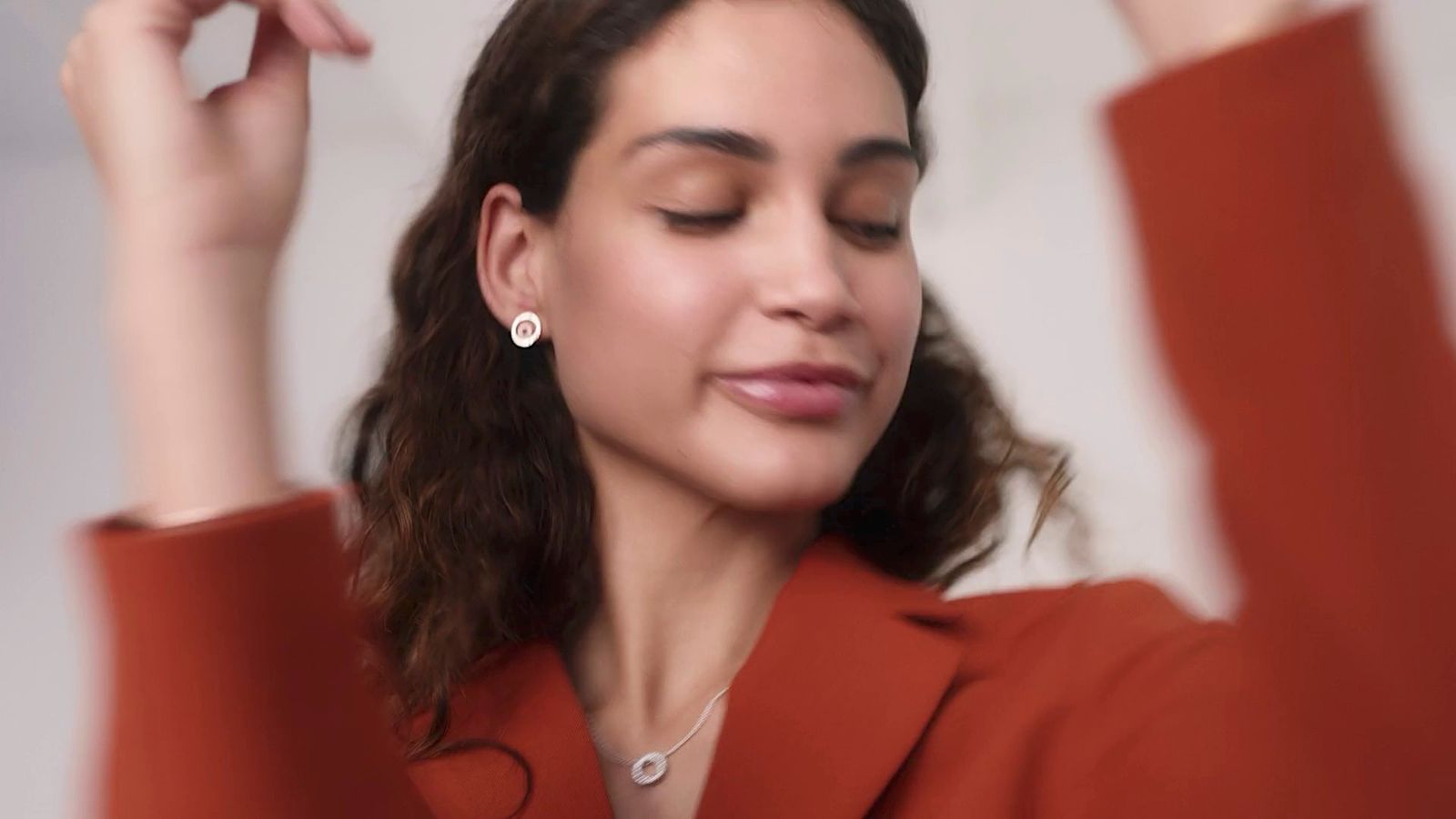 a woman wearing a red jacket and a pair of earrings