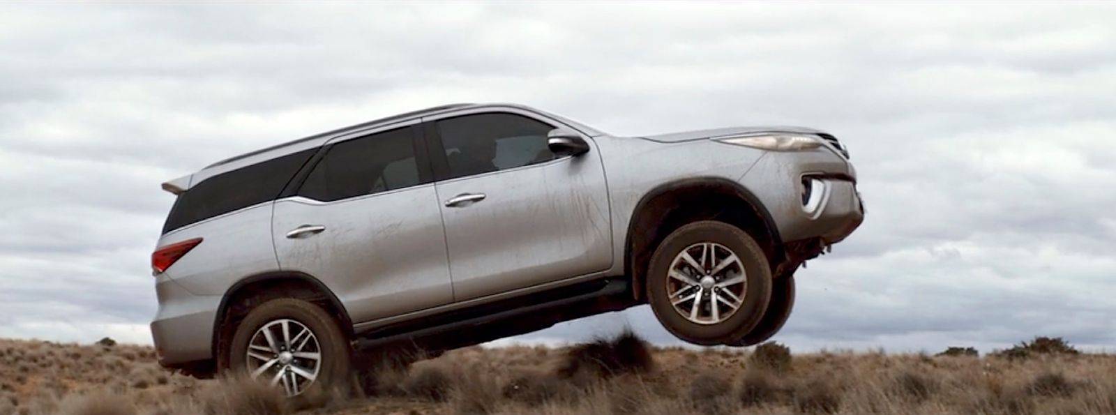 a silver four - door suv is jumping in the air