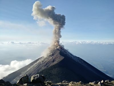 a large plume of smoke rising from the top of a mountain