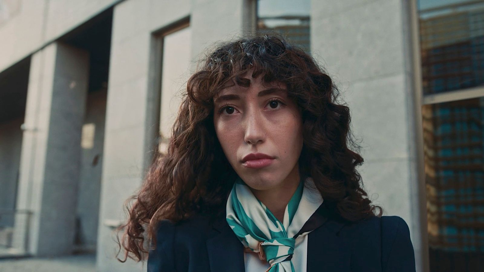 a woman with curly hair wearing a suit and tie