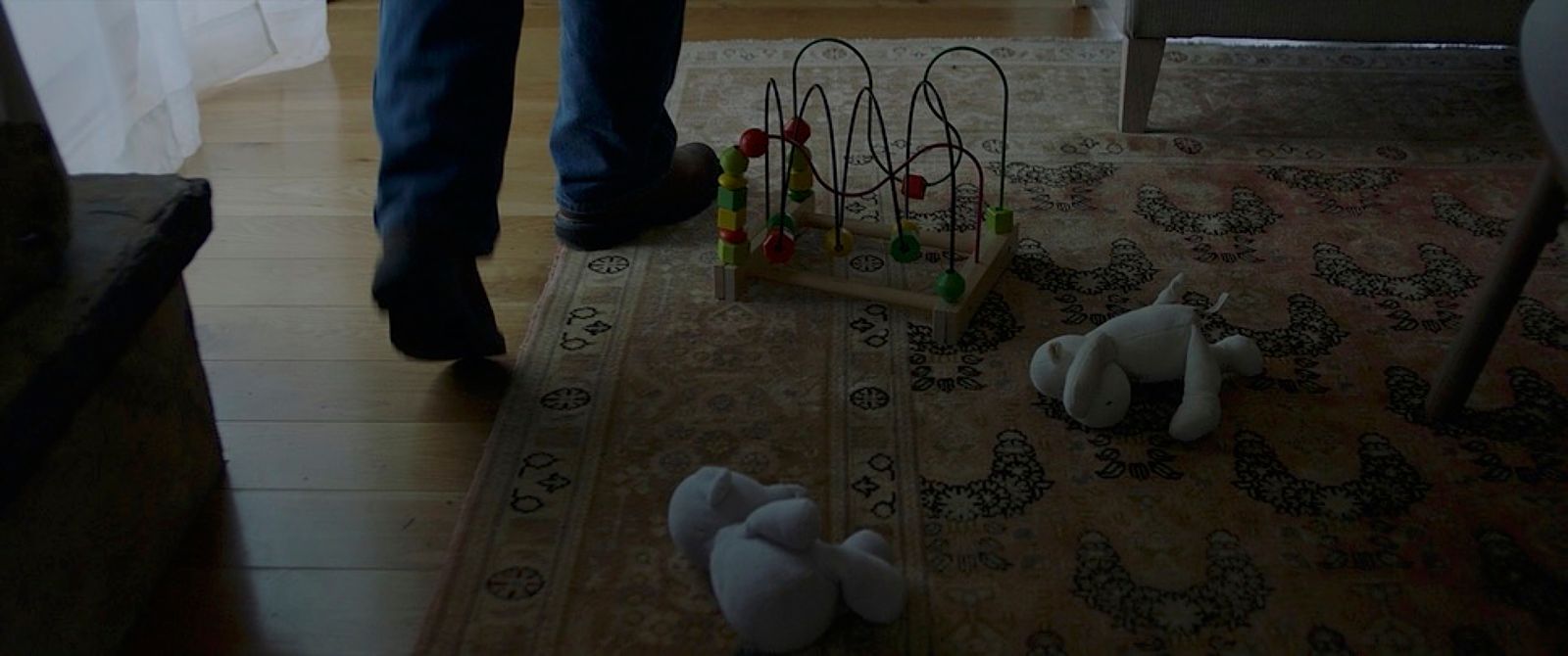 a person standing in a living room next to a pile of stuffed animals