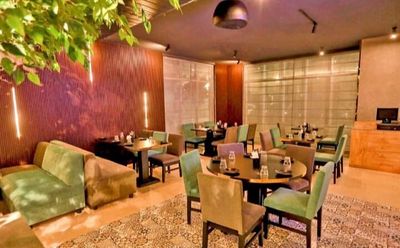 a restaurant with green chairs and wooden tables