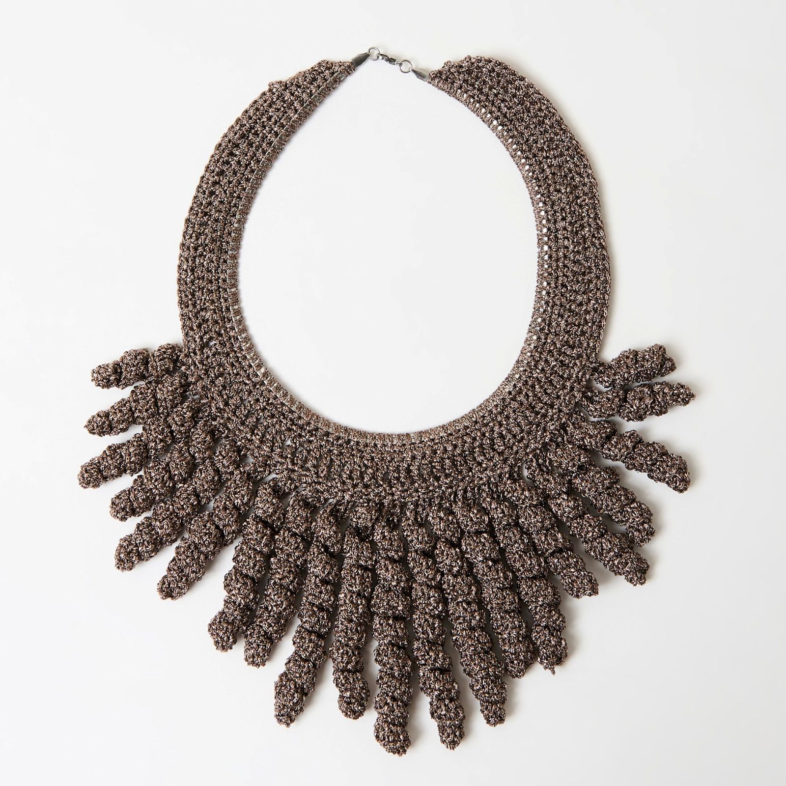 a crocheted necklace is displayed on a white surface