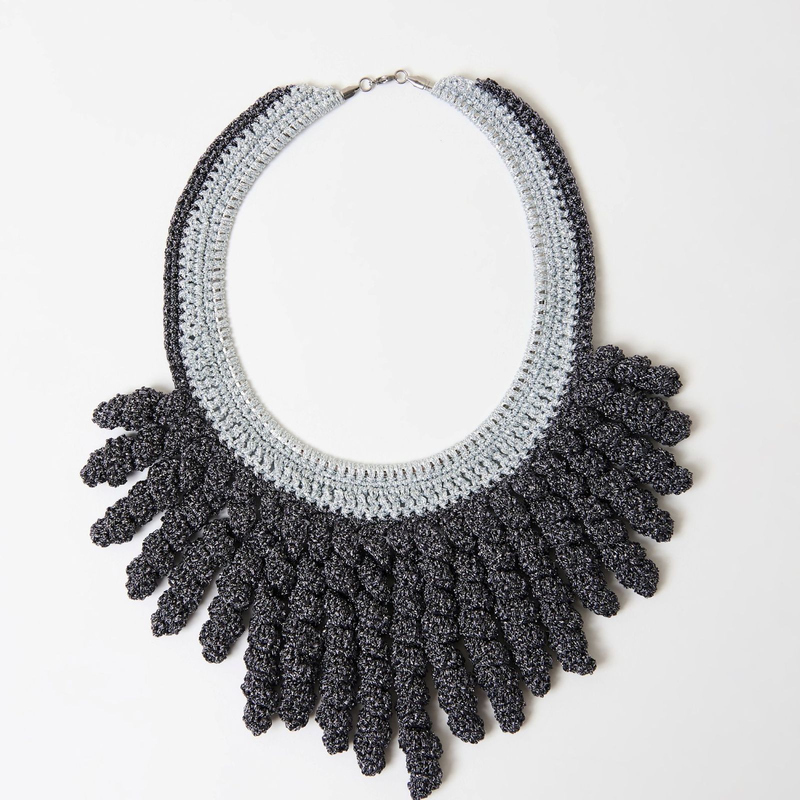 a black and white crochet necklace on a white surface